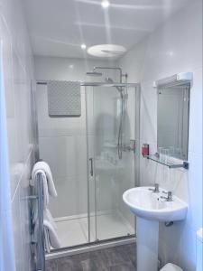 a white bathroom with a shower and a sink at Templestowe Hotel, Number One for Entertainment in Torquay in Torquay