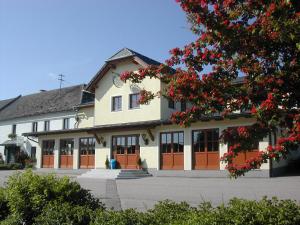 un edificio con porte arancioni e un albero con fiori rossi di Gasthof Pammer a Mardetschlag