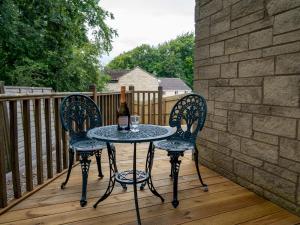 a table with two chairs and a bottle of wine on a deck at 3 Bedroom family home Parking Garden - Pass the Keys in Stroud