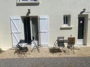 four chairs and a table in front of a building at Charming Apartment Gacé I 4P in Gacé