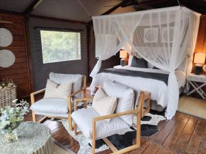 a bedroom with a canopy bed and two chairs at Barefoot Addo Elephant Lodge in Addo +229 photos