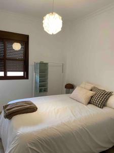 a bedroom with a large white bed with pillows at Ático Santa Lucía Terraza y Parking gratuitos in Alcalá de Guadaira