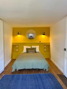 a bedroom with a bed with a yellow wall at Clos des Mésanges in Chisseaux