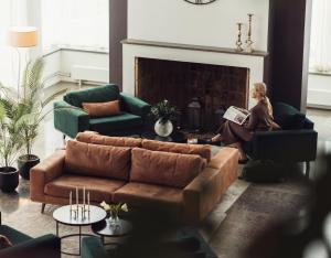 a woman sitting in a living room reading a book at Elite Stadshotellet Eskilstuna, Hotel & Spa in Eskilstuna