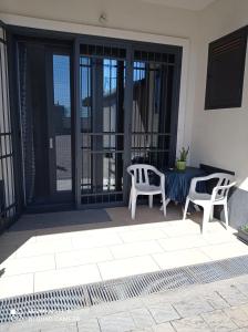 two chairs and a table on a patio with sliding glass doors at Le Mandorle Apartment in Belpasso