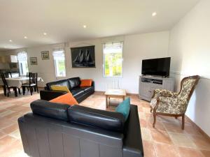 a living room with a black leather couch and chairs at Maison 3* rénovée, proche plage et sentier des douaniers, 4 pers, WIFI, parking, jardin, BBQ - FR-1-368-156 in Perros-Guirec
