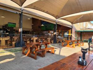 a group of wooden picnic tables in a restaurant at Best overnight modern & private with King size bed in Bloemfontein