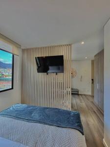 une chambre avec un lit avec une télévision à écran plat au mur dans l'établissement Luxury loft en el Parque Virrey, à Bogotá
