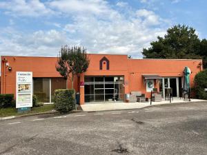a large orange building with a store on a street at Campanile NATURE - Bordeaux Sud Pessac in Pessac