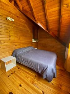 Un dormitorio con una cama en una cabaña de madera. en Huet Huet, en Villa La Angostura