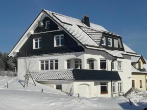 una casa bianca e nera nella neve di Ferienwohnung Hartmann a Winterberg