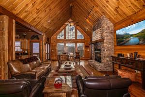a living room with leather furniture and a stone fireplace at Millstone Lodge in Bryson City