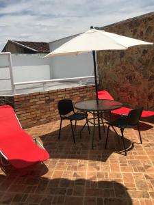 a table and chairs with an umbrella on a patio at Linda casa con jacuzzi in Roldanillo