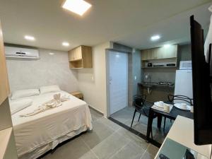 a bedroom with a bed and a table and a kitchen at KIPFLATS Residence in Fortaleza