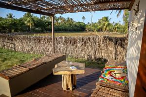 a porch with a bench and a table and a field at Villa Caju Atins in Barreirinhas