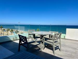 a table and chairs on a balcony with the beach at Seaside Apartments in Martil