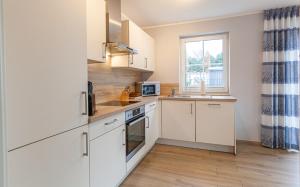 una cucina con mobili bianchi e una finestra di Seelöwe a Zingst