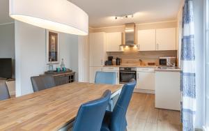 una cucina e una sala da pranzo con tavolo in legno e sedie blu di Seelöwe a Zingst Altre 13 foto