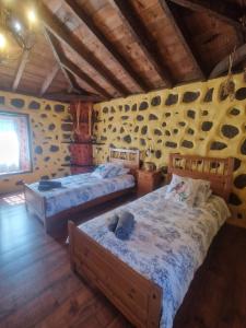 a bedroom with two beds and a wall with rocks at CHC - Casa Rural del Ciruelo in Buenavista del Norte