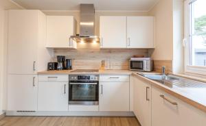 a kitchen with white cabinets and a sink and a microwave at Seeteufel in Zingst