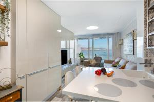 Una cocina blanca con una mesa y una sala de estar. en flat Belvedere las canteras beach, en Las Palmas de Gran Canaria