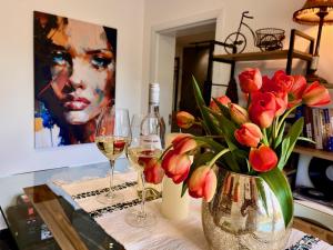 a table with two glasses of wine and a vase of flowers at Stay in Skopje - Prime Location Apartment in Skopje