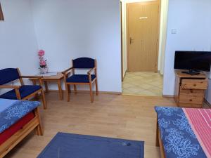 a living room with a tv and a table and chairs at Penzión Jana in Zborov