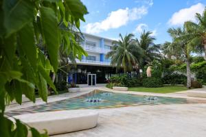 a pool in front of a building with palm trees at Luxury 1 bed apartment near Seven Mile Beach at The Grove - Villa Deluxe in Upper Land