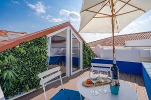 a table with wine glasses and an umbrella on a balcony at Host Wise - Elegant Loft with Historic Charm & Terrace in Portel