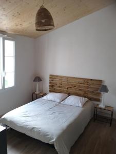 a bedroom with a large bed with a wooden headboard at maison 6-8 personnes, 300m de la plage in La Guérinière