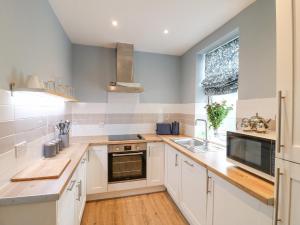 a kitchen with white cabinets and a sink at Alfreton Cottage in Alfreton
