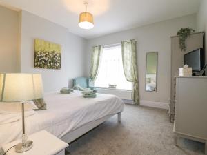 a bedroom with a bed with a lamp and a window at Alfreton Cottage in Alfreton