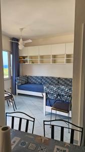 ein Wohnzimmer mit einem blauen Sofa und Stühlen in der Unterkunft Casa prima fila con Vista Mare in Isola Rossa