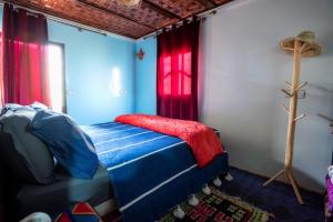 a bedroom with a bed with blue and red curtains at Gite akswal amssakrou in Ikis