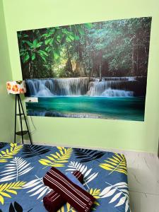 ein Gemälde eines Wasserfalls an einer Wand neben einem Bett in der Unterkunft Sri Bairav Cottage in Madurai