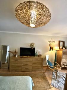 Zimmer mit einer Kommode mit einem TV und einem Kronleuchter in der Unterkunft Studio Céladon village vacances Ste Anne Guadeloupe in Sainte-Anne