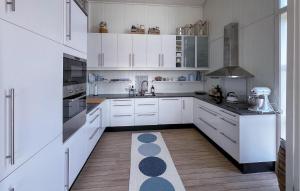 a kitchen with white cabinets and a wooden floor at 3 Bedroom Gorgeous Home In Lyngdal in Lyngdal