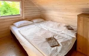 Cama en habitación de madera con 2 almohadas en Amazing Home In Sarbinowo With Wifi, en Sarbinowo