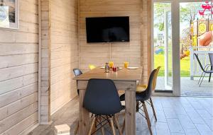 mesa de madera con sillas y TV en la pared en Amazing Home In Sarbinowo With Wifi, en Sarbinowo