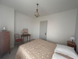 a bedroom with a bed and a chair and a chandelier at Maison au coeur du Périgord Vert in Javerlhac-et-la-Chapelle-Saint-Robert