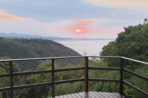 a view of the ocean from a balcony with the sun setting at Mount 'n Sea Retreat Studio in Victoria Bay