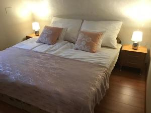 a bedroom with a bed with pillows and two lamps at Kert Apartman in Cserkeszőlő