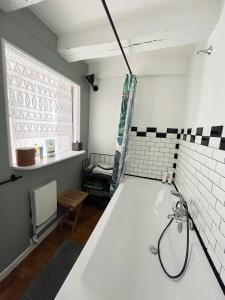 La salle de bains est pourvue d'une baignoire blanche et d'une fenêtre. dans l'établissement Charmante maison de village, à Sénaillac-Lauzès