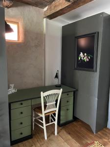 un bureau avec une chaise à côté d'un mur dans l'établissement Charmante maison de village, à Sénaillac-Lauzès