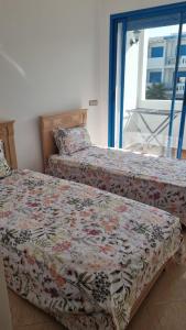 two beds sitting next to each other in a bedroom at Très bel Appartement avec Piscine et Jardin in Mansouria +13 photos