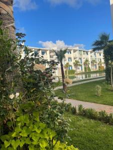 a building with a palm tree in a park at Très bel Appartement avec Piscine et Jardin in Mansouria