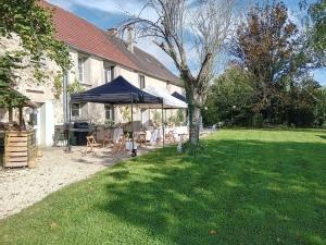 a house with a tent and chairs and a yard at La Ferrière in Marolles-en-Brie