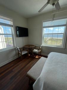 a bedroom with a bed and a table and two windows at Casa Marina Hotel & Restaurant - Jacksonville Beach in Jacksonville Beach