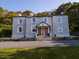 une grande maison blanche avec une porte d'entrée dans l'établissement Dalegarth Hall Farm Cottage 1, à Holmrook