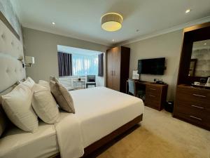 a bedroom with a white bed and a television at The Fig Tree Hotel in Shanklin